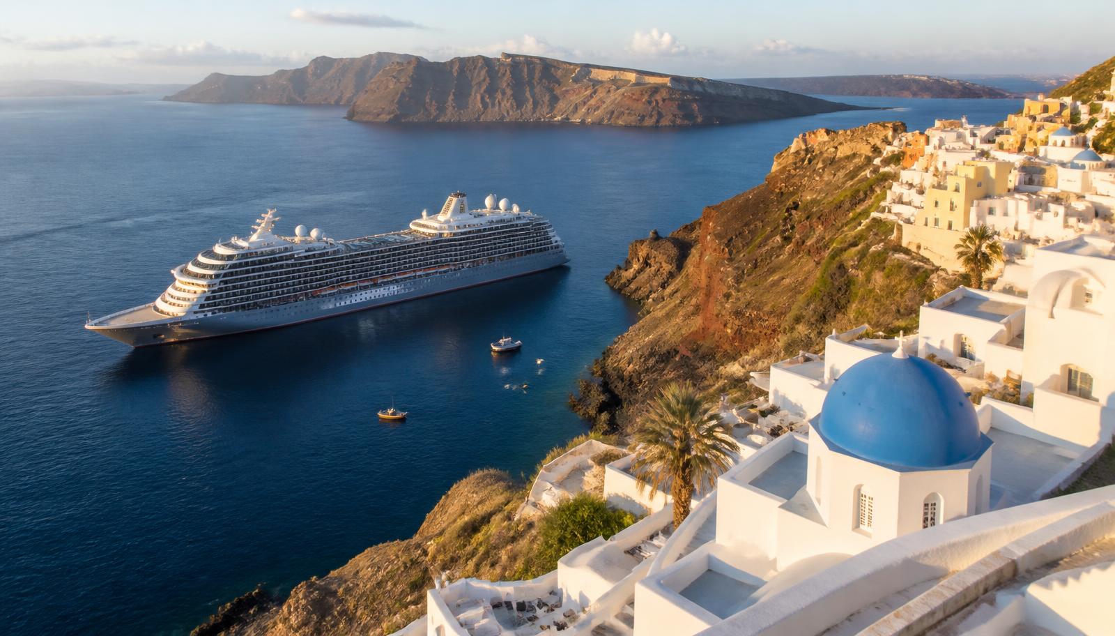 Navire de croisière au mouillage devant un village blanc des Cyclades